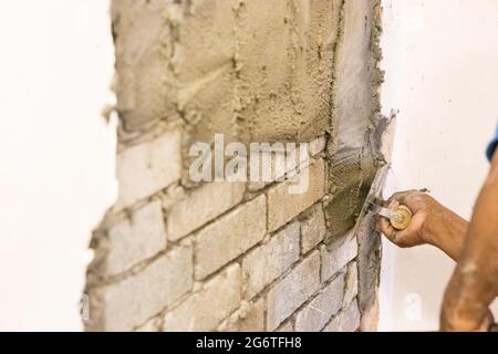 Worker plastering cement mortar on brick wall with trowel Stock Photo