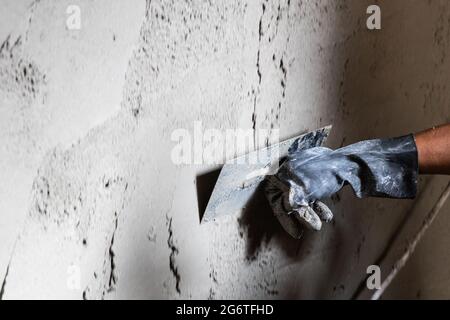 Worker plastering cement mortar on concrete wall with trowel Stock Photo