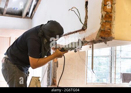 Worker drilling on wall to create cavity for electric power cables in home renovation Stock Photo