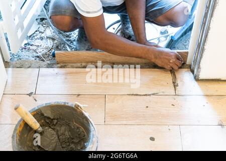 Worker installing ceramic floor tile at door edge Stock Photo