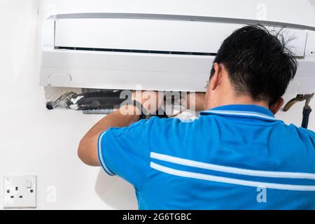 Technician installing indoor air conditioner condenser unit on wall Stock Photo