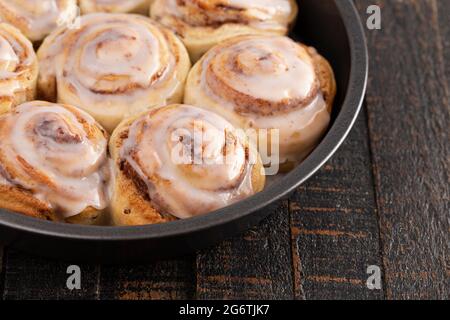 Frosted Cinnamon Rolls in a Pan on a Rustic Wooden Table Stock Photo