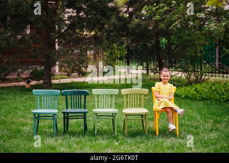 lifestyle portrait of a girl in dresses sitting on chairs in an open-air cinema in the backyard, family vacation on weekends on summer evenings Stock Photo