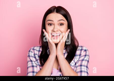 Photo of sweet impressed young woman wear plaid shirt smiling arms cheeks isolated pink color background Stock Photo