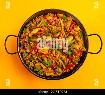 spanish paella rice with chicken on yellow background Stock Photo