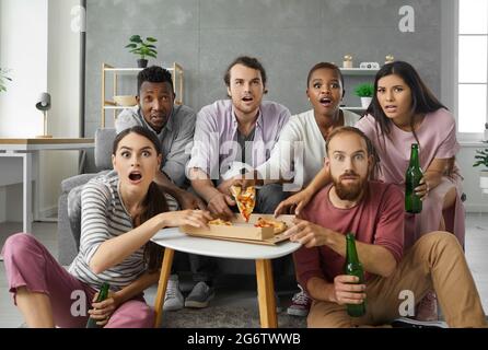 Happy friends or football fans watching soccer on tv and celebrating victory at home. Stock Photo
