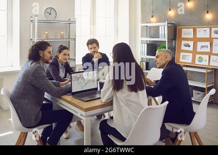 Business team discussing their plans sitting around office table in corporate meeting Stock Photo