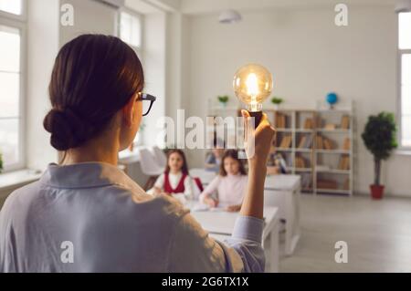 Best teacher with idea light bulb inspires elementary children at lesson Stock Photo