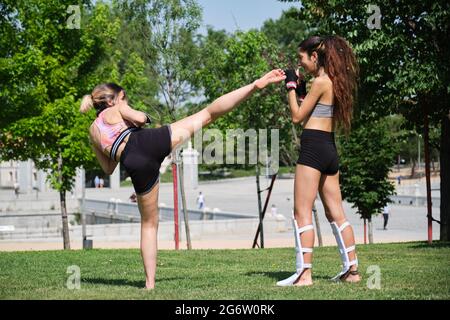 Two women practicing muay thai, boxing, kickboxing, in a park. Sport outdoors. Stock Photo