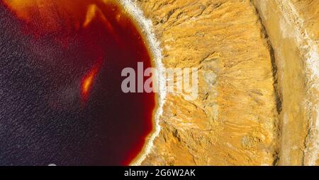 Shore of acidic lake in abandoned open pit copper mine, aerial view directly above. Red water is polluted with acid and heavy metals Stock Photo