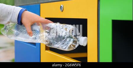 Bin. Close up hand put bottle plastic trash can. Child trash recycle bin. Kid recycle plastic garbage can. Child hand throwing plastic bottle Stock Photo