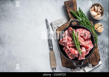 Raw diced meat cubes with bone in a pan. White background. Top View. Copy space Stock Photo