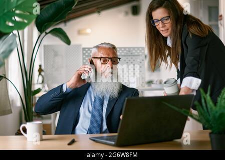 Multi generational people working inside modern office - Focus on senior man face Stock Photo