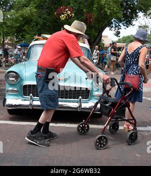 An elderly man using a wheeled rollator upright walker visits a classic car show in Santa Fe, New Mexico. Stock Photo