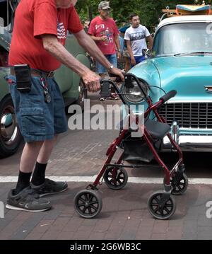 An elderly man using a wheeled rollator upright walker visits a classic car show in Santa Fe, New Mexico. Stock Photo