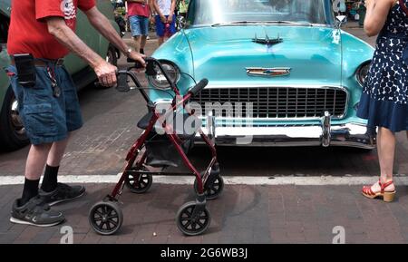 An elderly man using a wheeled rollator upright walker visits a classic car show in Santa Fe, New Mexico. Stock Photo