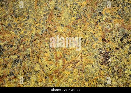Golden granite, polished surface of natural stone with small black inclusions close-up. Background, pattern, texture. Stock Photo