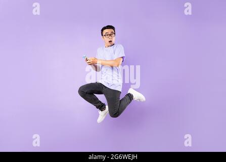 Portrait of a jumping asian man, isolated on purple background Stock Photo