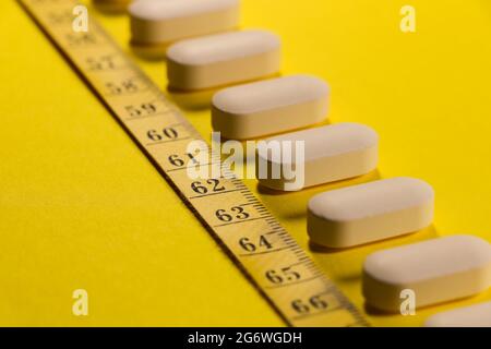 Pills With Measuring Tape Diagonal Line On Yellow Stock Photo
