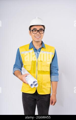 Smiling young asian civil engineer wearing helmet hard hat standing on isolated white background. Mechanic service concept. Stock Photo