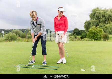 Woman looking at male golfer putting ball in green Stock Photo