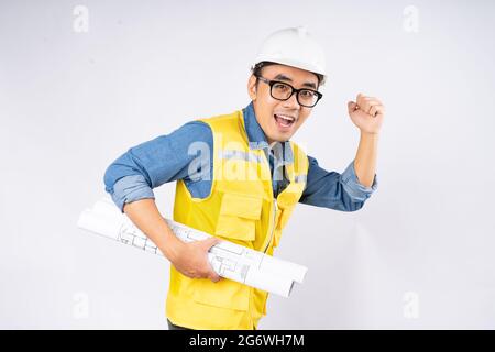 Smiling young asian civil engineer wearing helmet hard hat standing on isolated white background. Mechanic service concept. Stock Photo