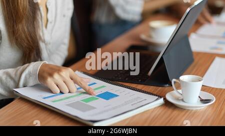 Closed up a businesswoman looking on the financial papers with laptop and a cup of coffee on the office desk Stock Photo