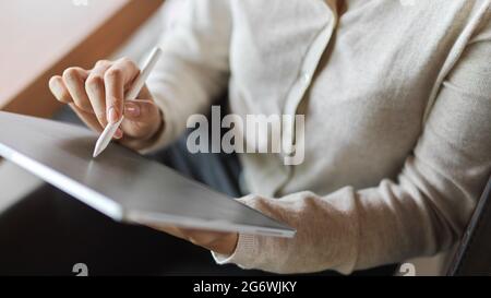 Businesswoman working on tablet while holding stylus pen Stock Photo