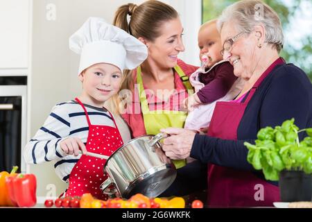 Mom, dad, granny and grandson together in kitchen preparing healthy food Stock Photo