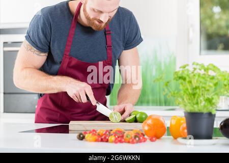 Man preparing veggies for cooking in kitchen Stock Photo