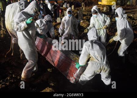 East Jakarta, Indonesia. 08th July, 2021. (Editors note image depicts death) Undertakers wearing Personal Protective Equipment suits (PPE) lower the coffin of a covid-19 victim for burial at Rorotan public cemetery. Indonesia on Thursday reported a new daily record of 38,391 coronavirus infections, plus 852 new fatalities, its second-highest daily death toll, official data showed. Indonesia has recorded 63,760 coronavirus deaths so far and more than 2400000 million cases in total. Credit: SOPA Images Limited/Alamy Live News Stock Photo