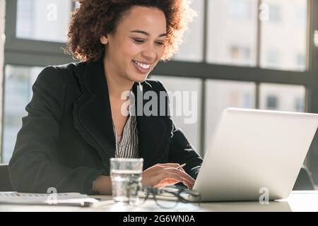 Portrait of African American female expert analyzing printed business report while sitting at desk in the office Stock Photo