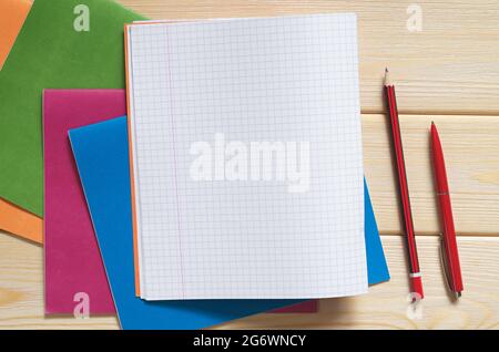 Various school notebooks, one open, pen and pencil on a wooden desk, top view. Space for text Stock Photo