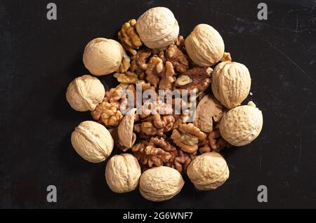 Walnuts and kernels Whole walnuts and kernels on old black metal background, top view Stock Photo