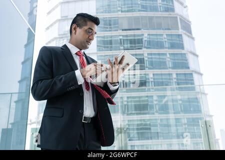 Indian businessman analyzing financial report on a tablet PC indoors at the office Stock Photo
