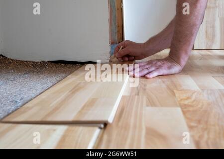 Caucasian man installing wood parquet board during flooring work Stock Photo