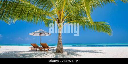 Beautiful tropical island scenery, two sun beds, loungers, umbrella under palm tree. White sand, sea view with horizon, idyllic blue sky, calmness Stock Photo