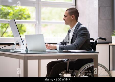 Handicapped Businessman Using Laptop Computer In Office Stock Photo