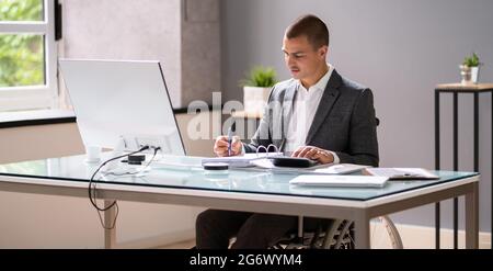 Disabled Accountant In Wheelchair Working Using Computer Stock Photo