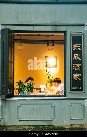 A couple dining seen through a window at Dongxin Restaurant on Wukang Road in the former French Concession, Shanghai, China. Stock Photo