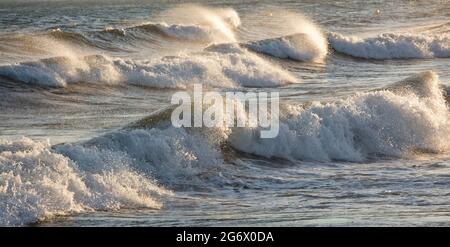 Waves splashed over rocks on a very windy day at sunset (golden hour) Stock Photo