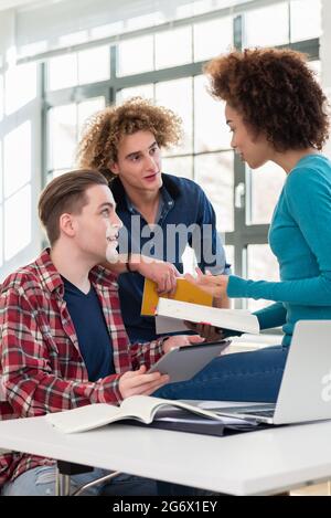 Three involved students sharing ideas and opinions about different topics and new information learned during courses at the university Stock Photo