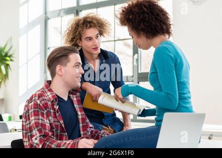 Three involved students sharing ideas and opinions about different topics and new information learned during courses at the university Stock Photo