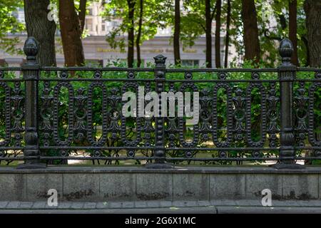 Antique black cast-iron fence with ornate ornament. Stock Photo