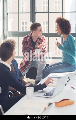 Cheerful students having a funny loud conversation  during break in the classroom of a modern university with international students Stock Photo
