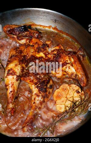 oven roasted baby chicken with onions and galic in a pan, dish known as spatchcock Stock Photo