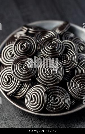 Spiral from liquorice candy on black plate. Stock Photo
