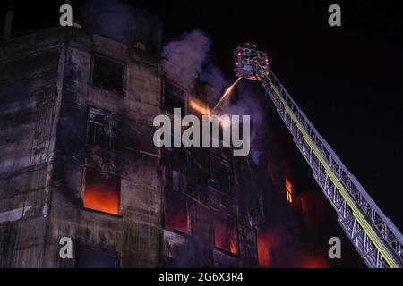 Firefighters try to extinguish a fire at a building at Bonani area in ...