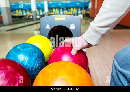 Close-up of a person's hand picking bowling ball from rack Stock Photo