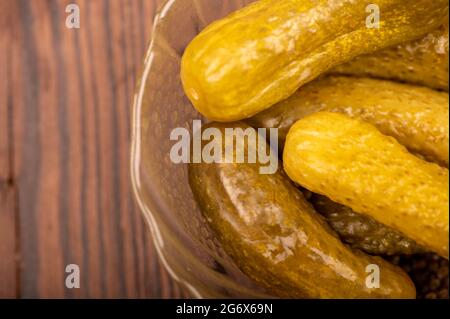 Pickled cucumbers in a glass dish on a wooden table. Close-up Selective focus Stock Photo